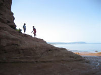 Kids climbing on rocks with Blomidon in background
